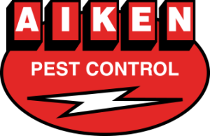 Logo for Aiken Pest Control. The design features the words "AIKEN" in bold white capital letters inside red rectangles above "PEST CONTROL" in white on a red oval background. A white lightning bolt graphic crosses below the text.